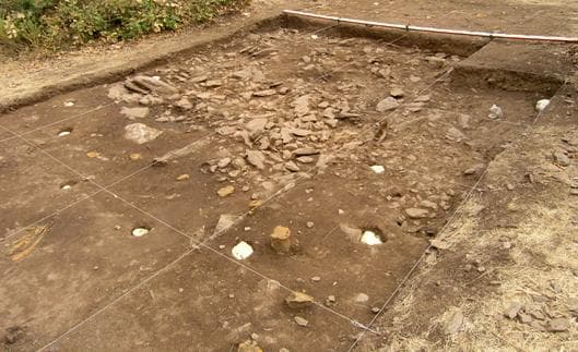 Fig. 6 – A Cabana 5 no final da Campanha 3 (2005). Além do respectivo empedrado de base são visíveis cheios a poliuretano expandido de cor branca os respectivos buracos de poste. De cor amarelada são visíveis os moldes internos em poliuretano expandido que preenchem os buracos de poste da Cabana 1.